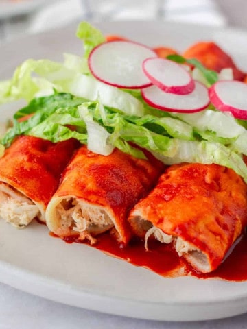 Up close view of chicken filled red enchiladas.