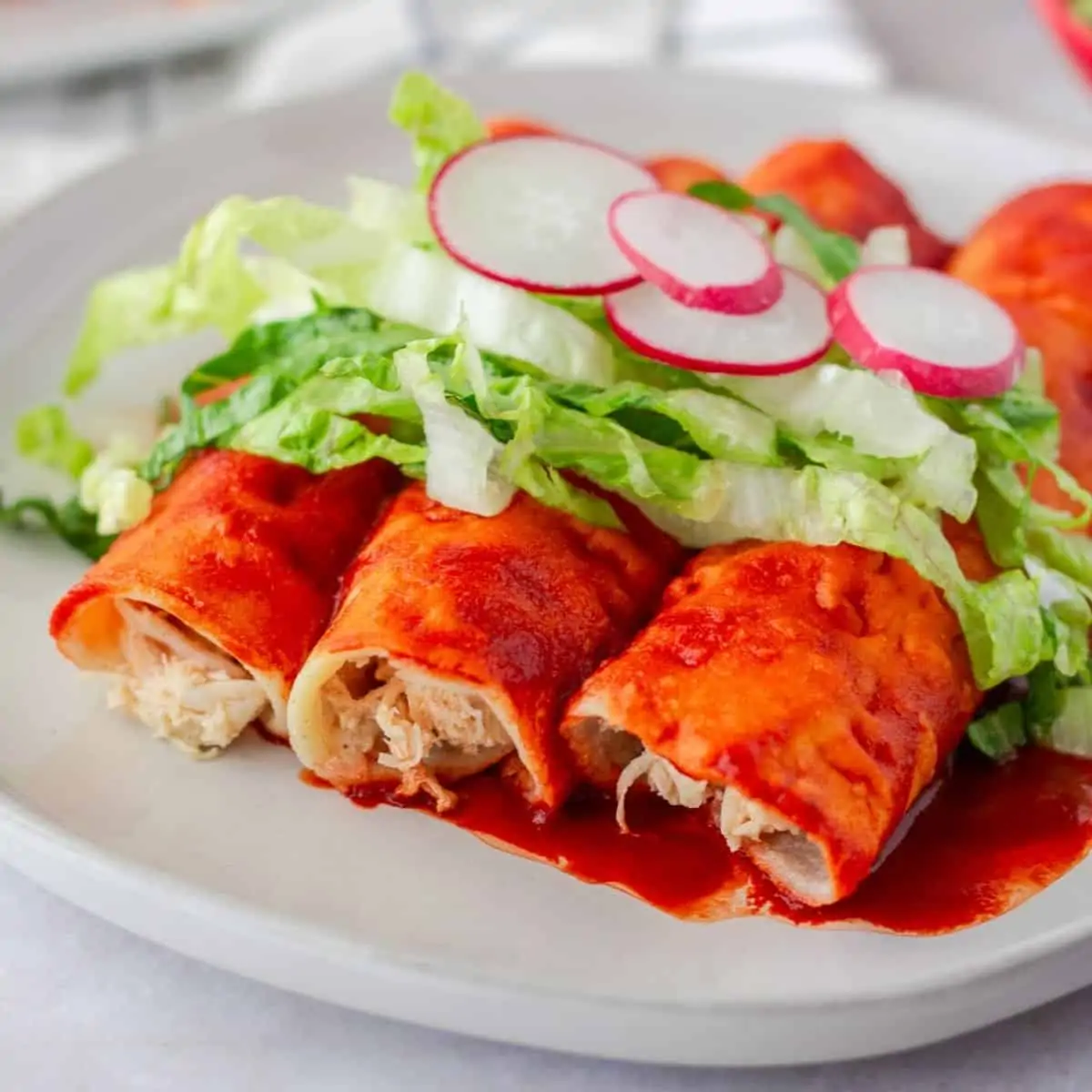 Up close view of chicken filled red enchiladas.