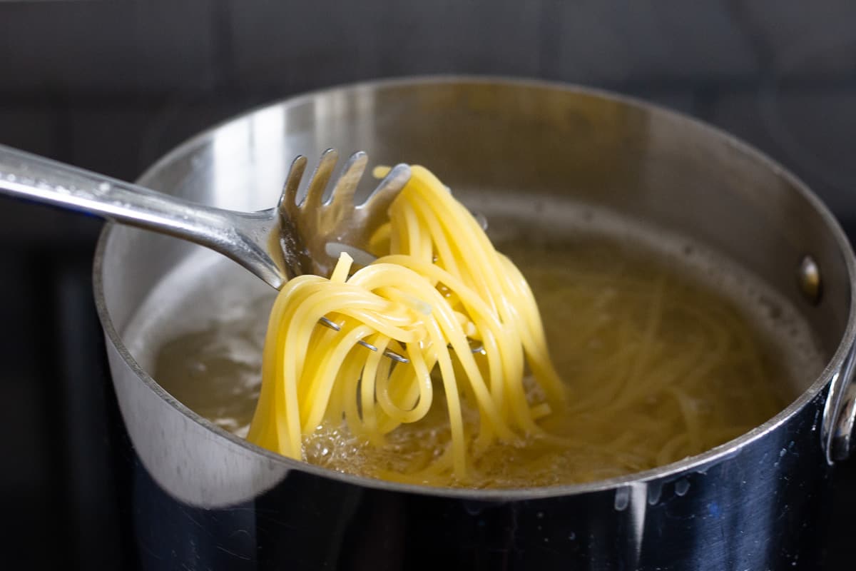 Spaghetti noodles being cooked in a pot.