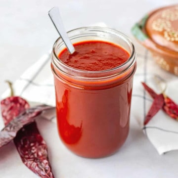 Feature image of enchilada sauce in a glass mason jar with dried chiles on the side.