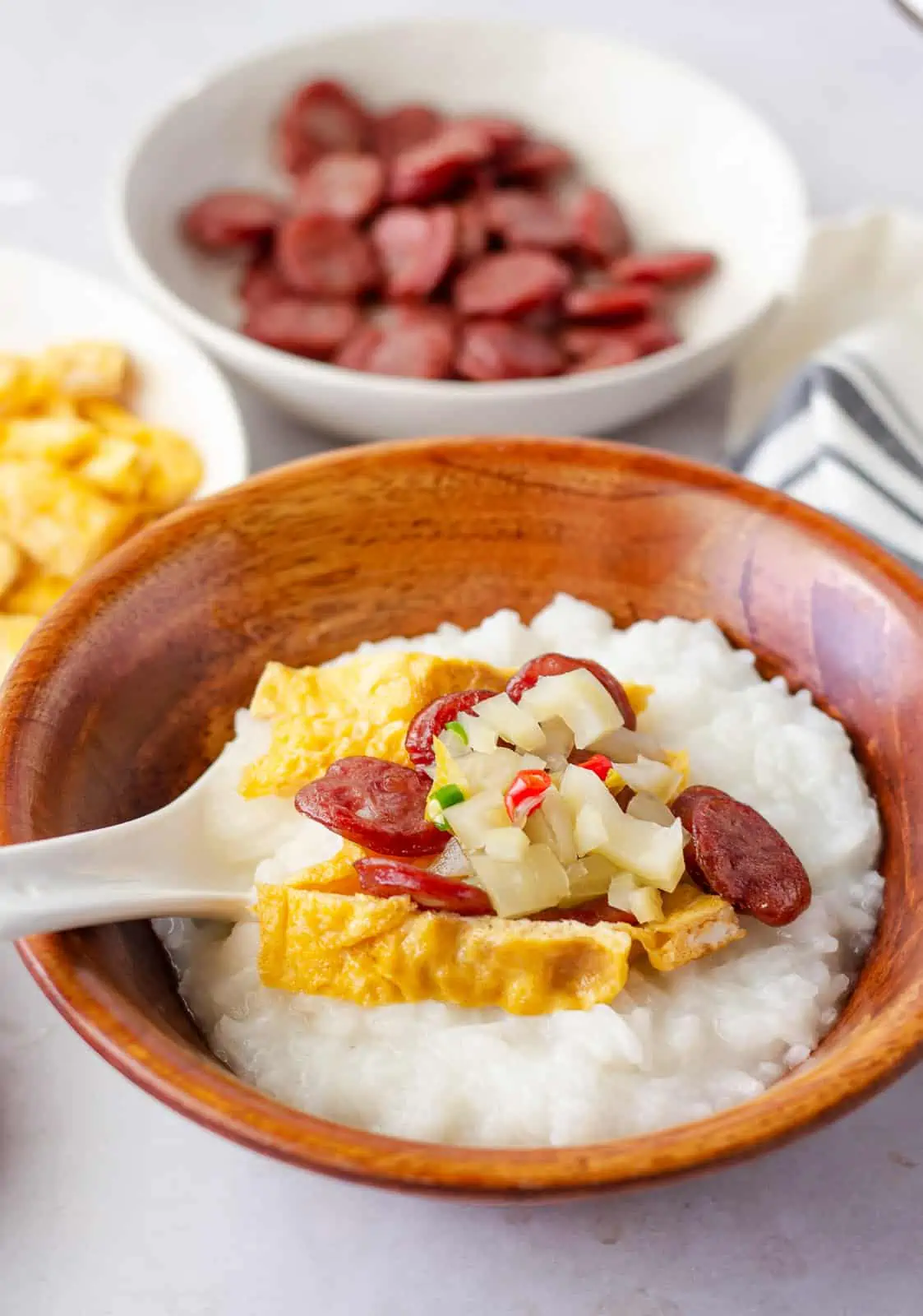 Garnished rice soup with side of sausage and fried egg.