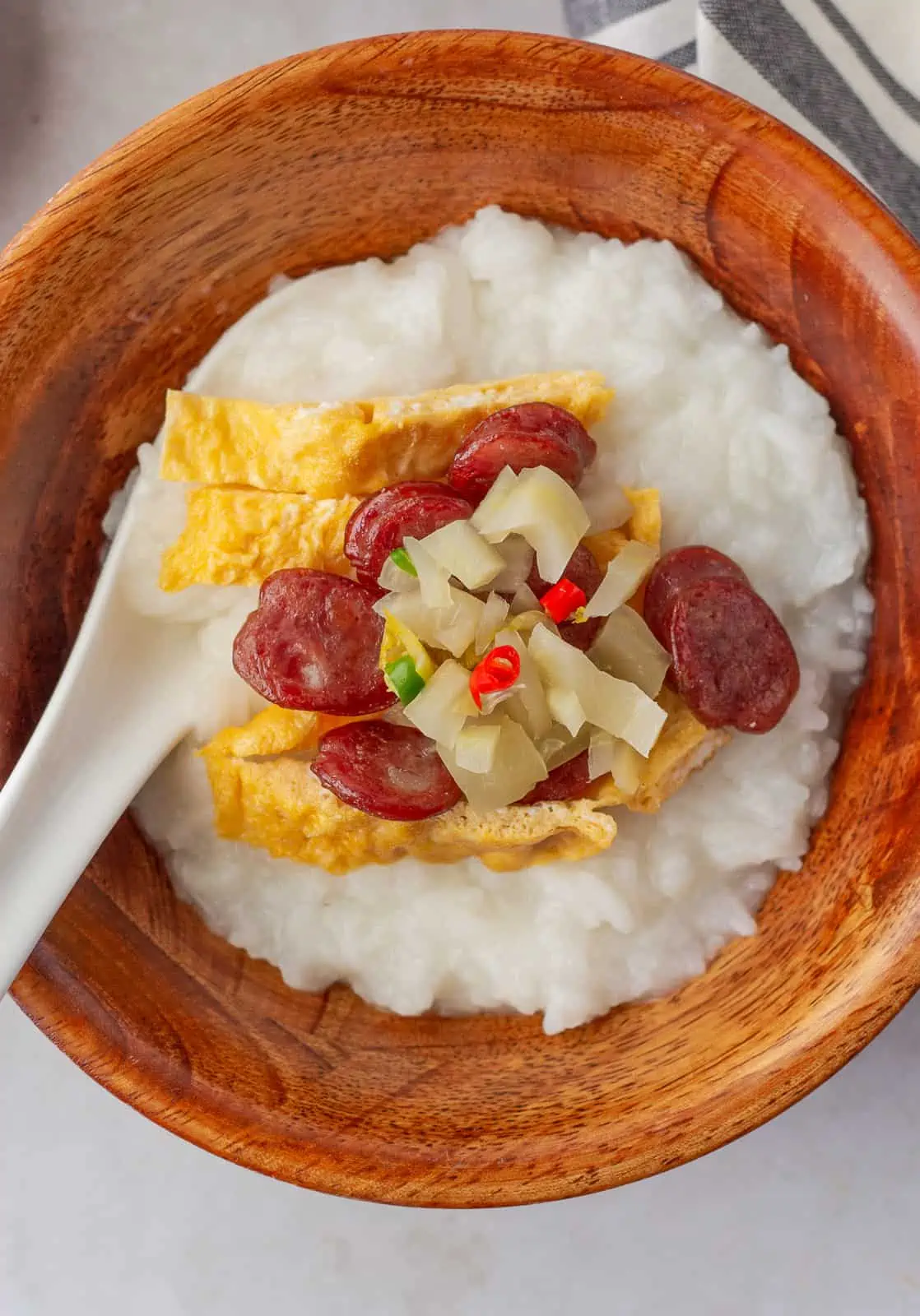 Overhead view of khao tom in a wooden bowl with toppings.