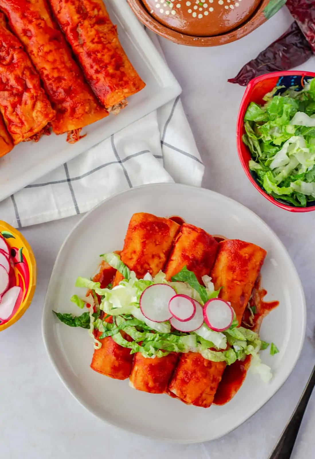 Overhead view of enchiladas rojas with toppings.