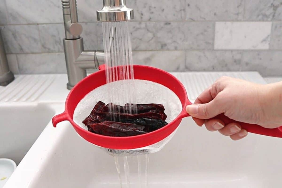 Rinsing dried chiles in a strainer.