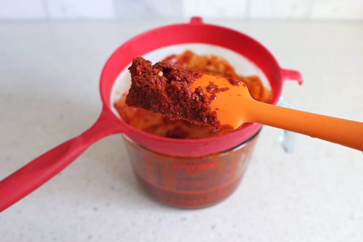 Pulp and seeds on spatula from strained enchilada sauce.