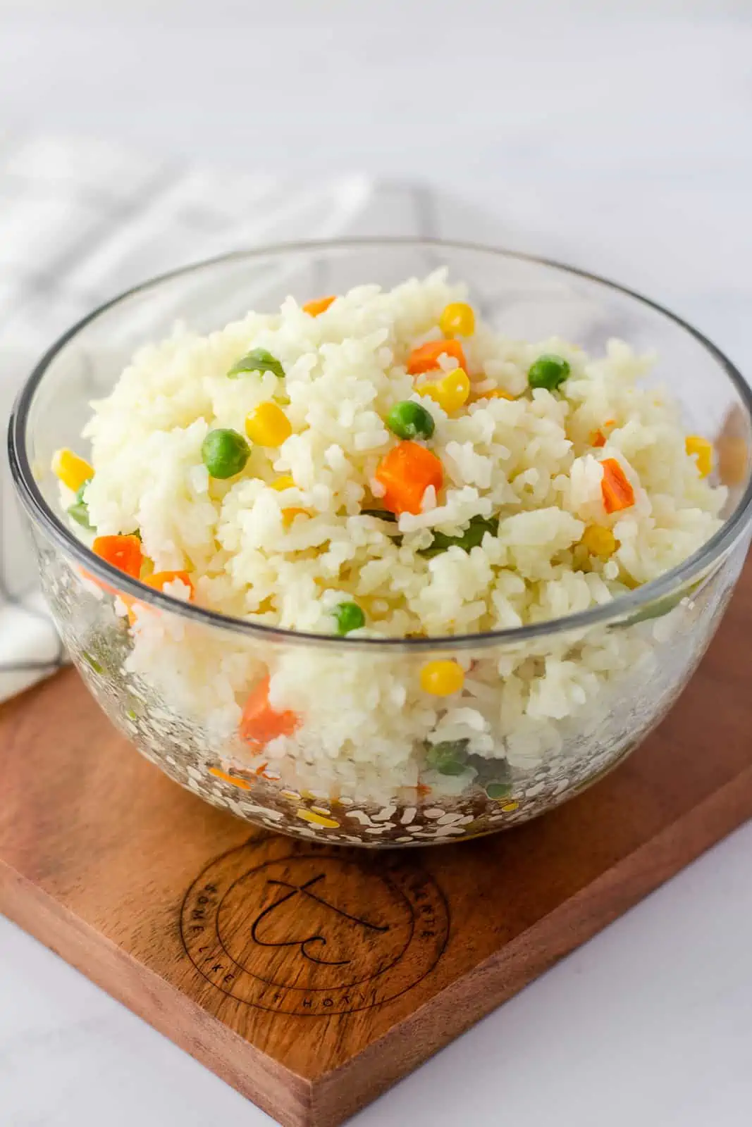 Rice in a glass bowl on a wood board.