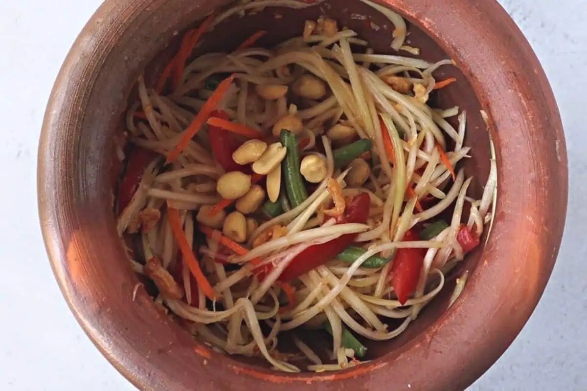 Papaya Salad in a brown mortar.