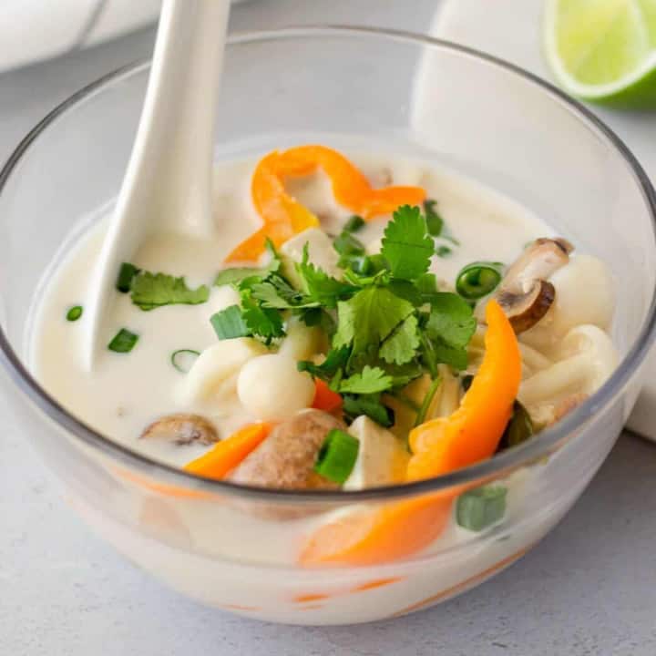 Up close view of tofu tom kha in a glass bowl.