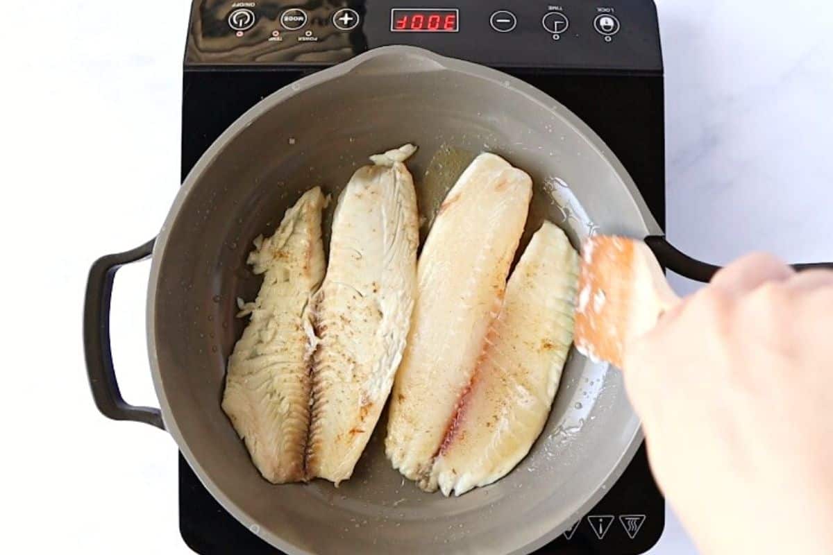 Cooking tilapia in a skillet.
