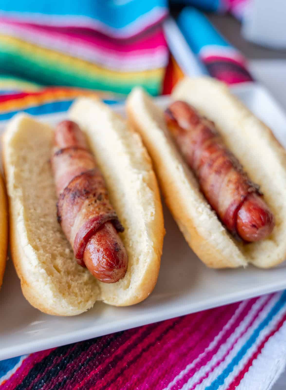 Bacon wrapped hot dogs in buns.
