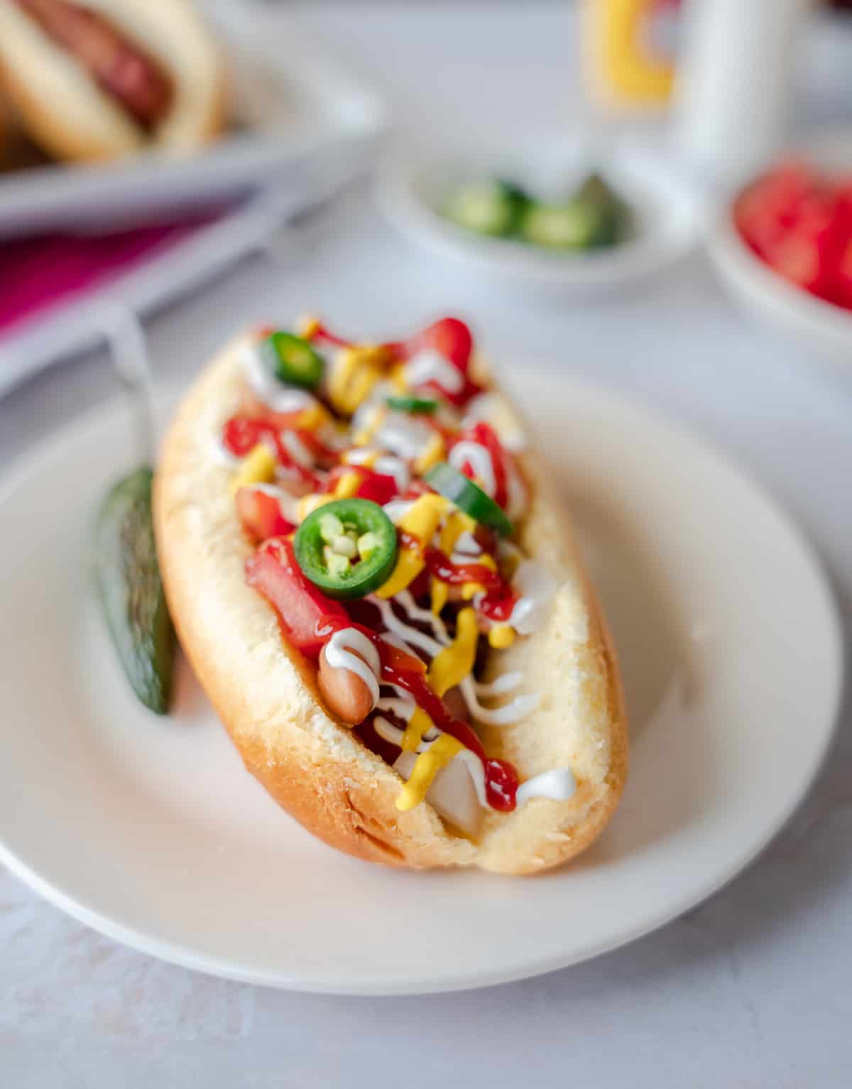 Hot dog with toppings on a round plate.