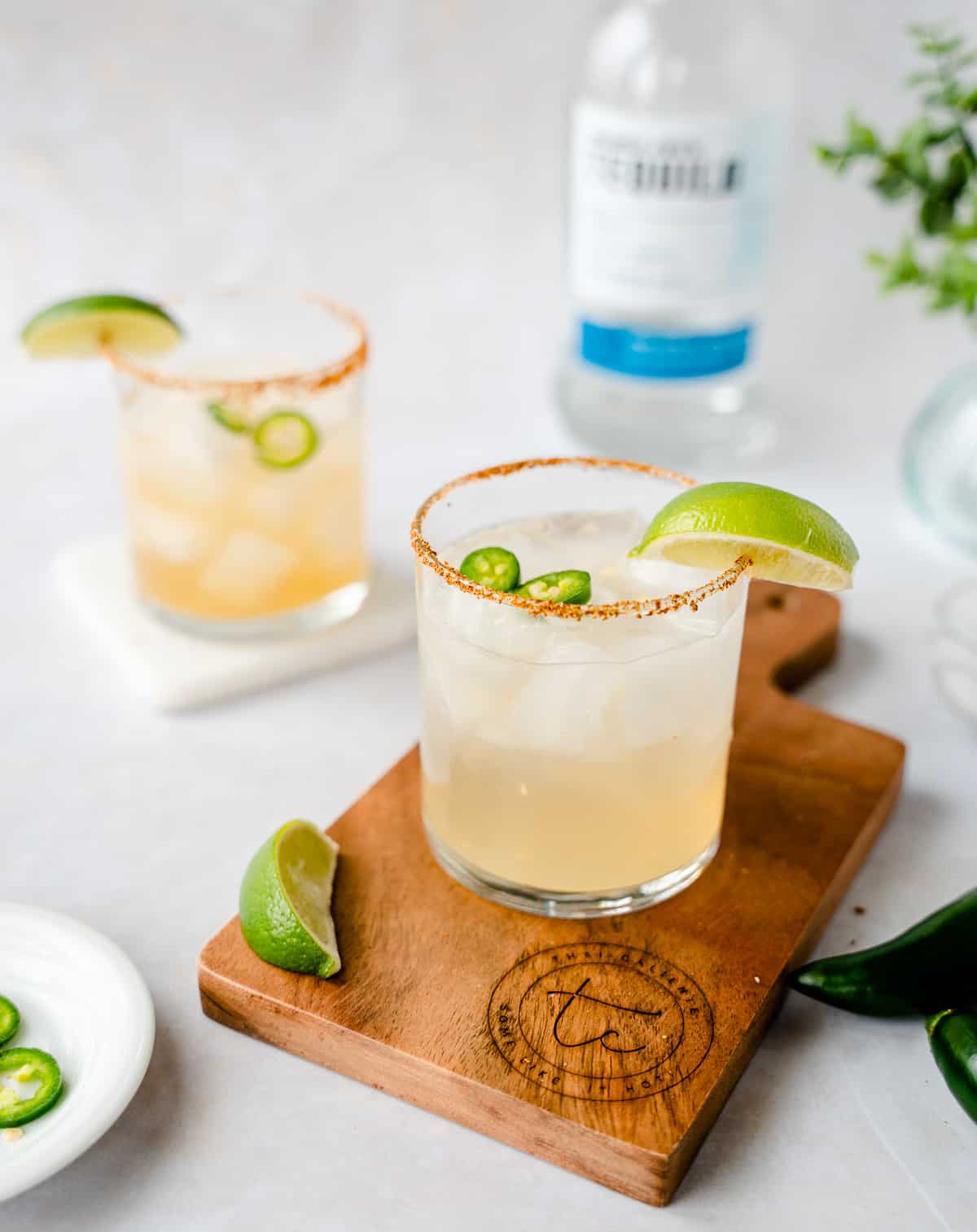 2 glasses garnished with limes and jalapeno slices.