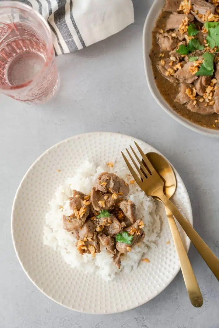 Overhead view of Moo Kratiem on a plate with rice and some on a serving plate.