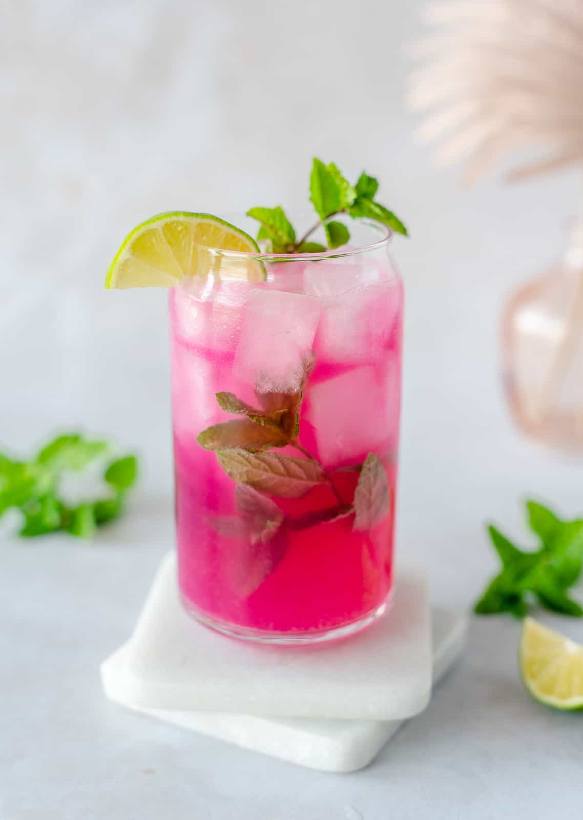 Prickly Pear Mojito on white coasters and garnished with mint and lime.