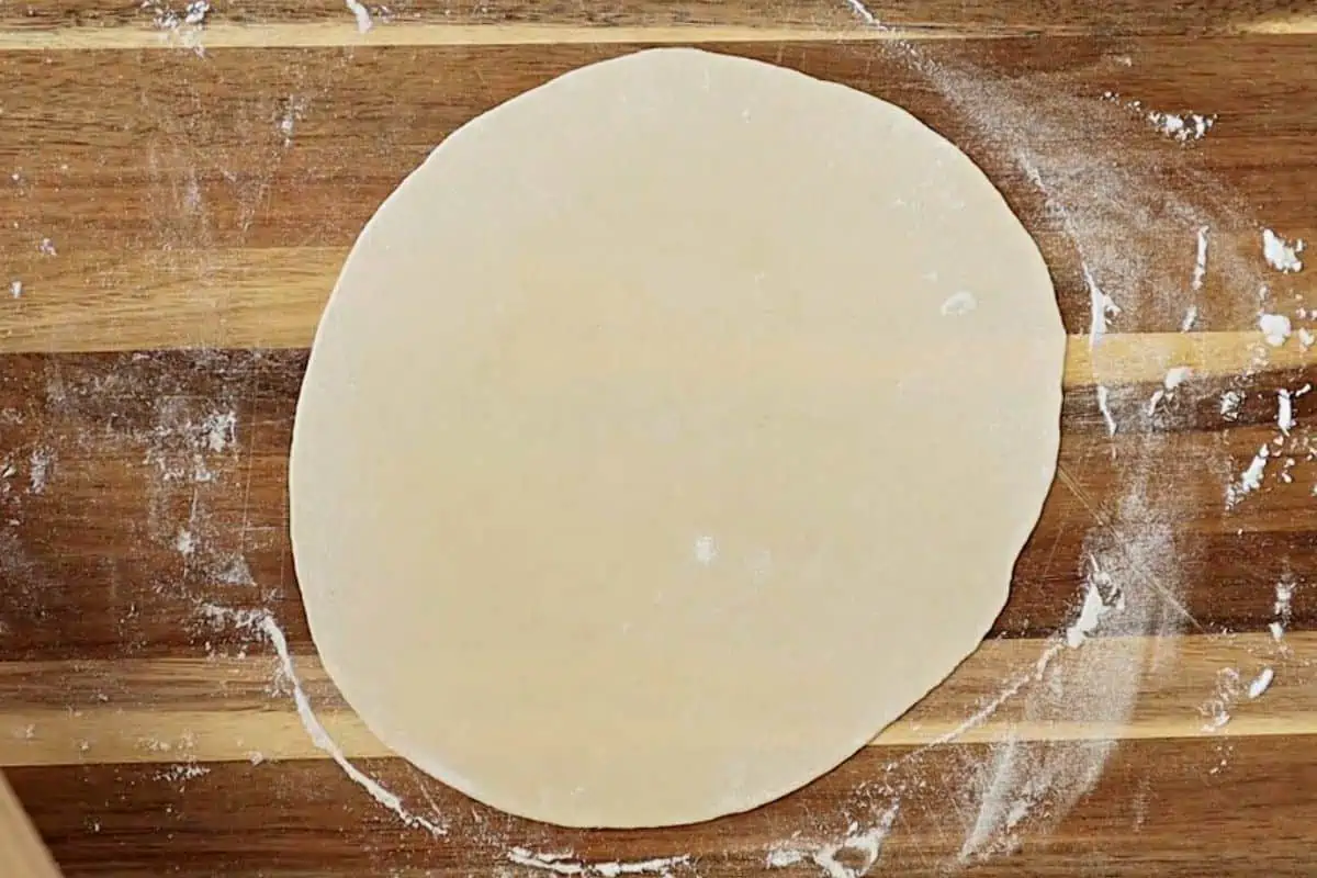 Rolling out flour tortilla on a board.