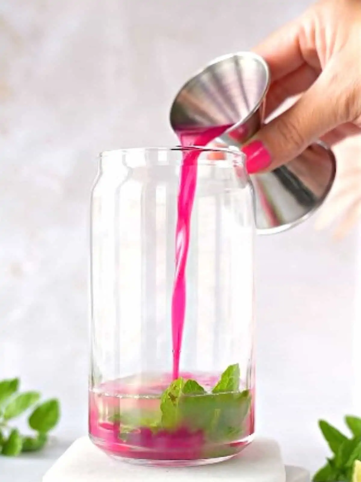 Hand pouring prickly pear syrup into a glass.