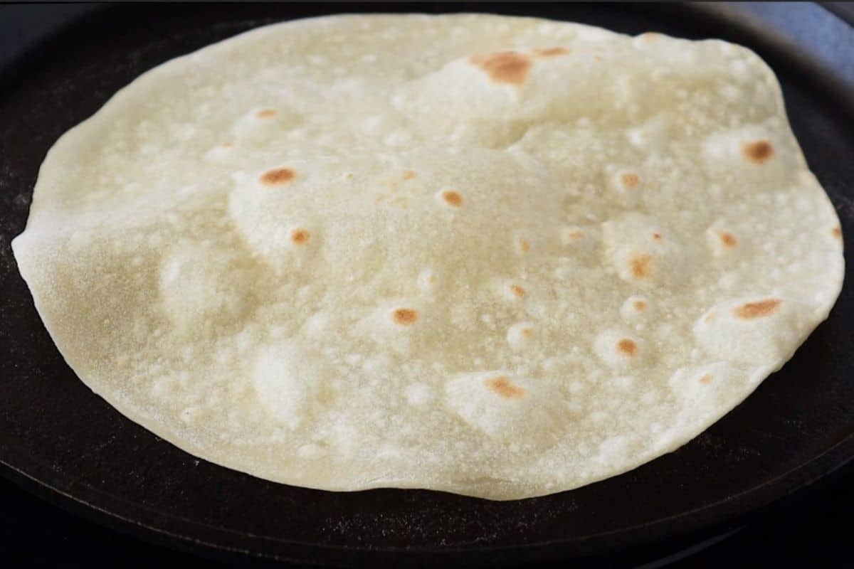Flour tortillas being cooked on a griddle.