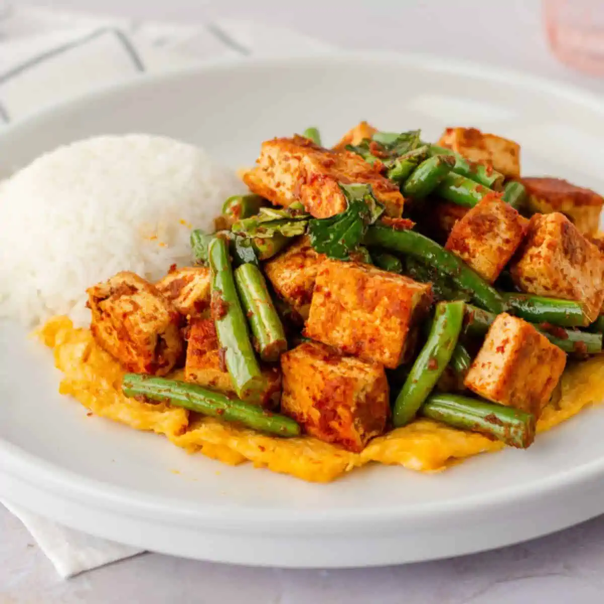 Feature image of pad prik tofu on a plate with rice.