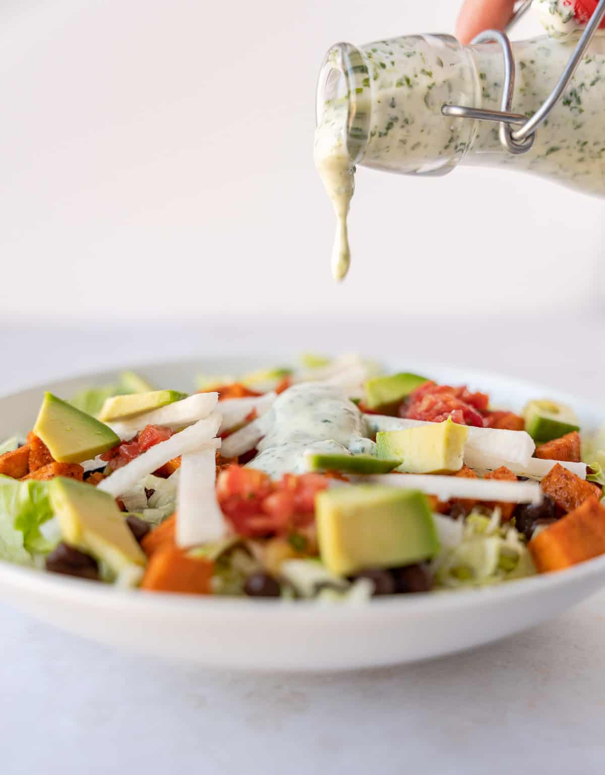 Dressing being poured on top of a salad.