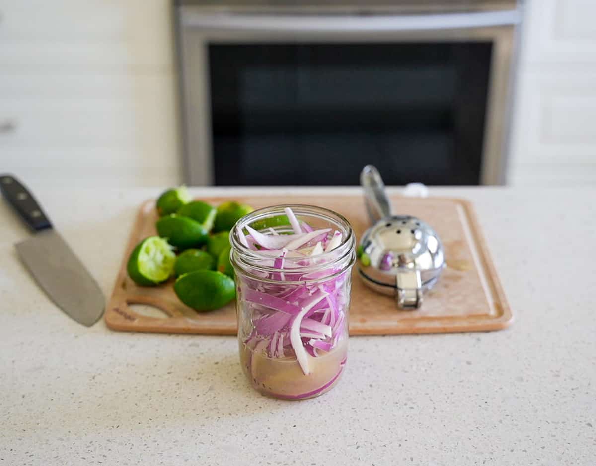 Sliced onions in a jar with lime juice.