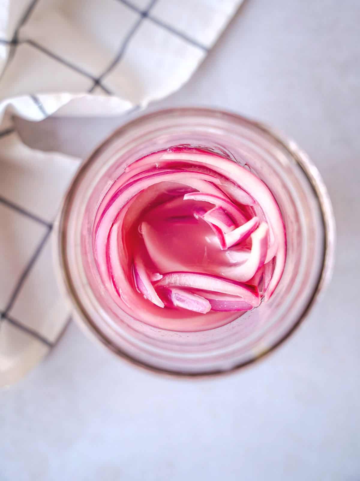 Overhead view of pickled red onions in a mason jar.
