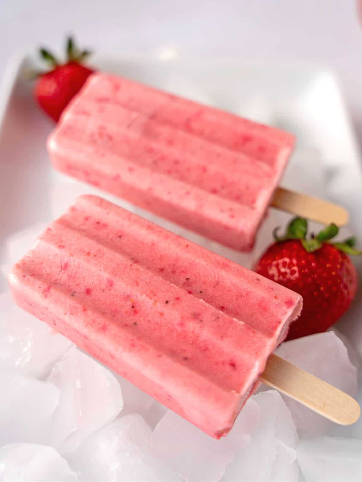 Two strawberry popsicles on ice.