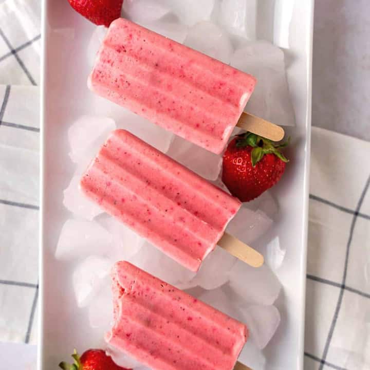 Feature image of three paletas de fresas con crema on a plate.