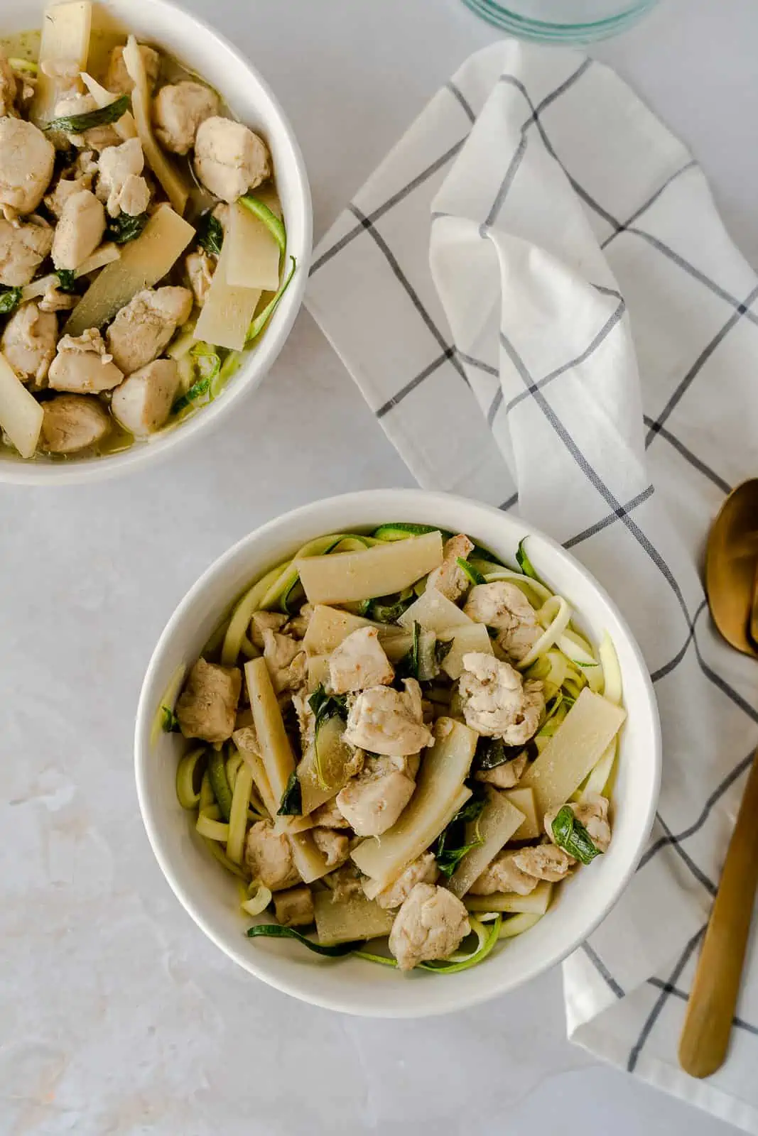 Overhead view of 2 bowls with green curry and a napkin on the side.