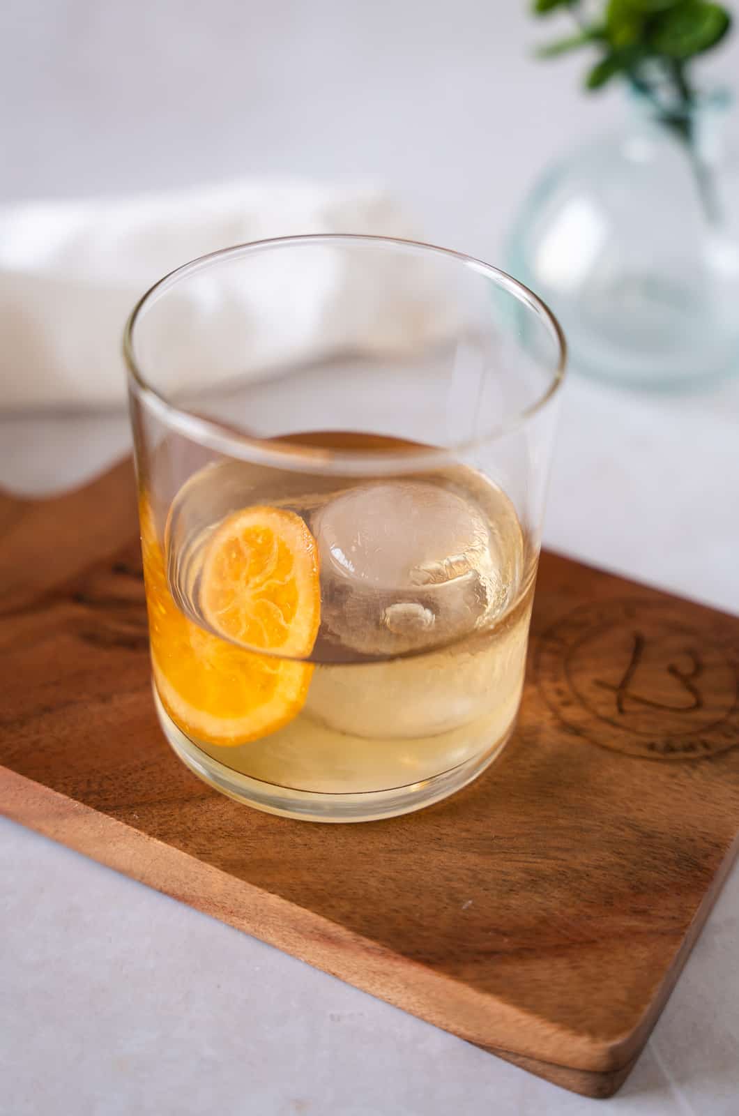 Cocktail in a glass with an orange slice and ice ball.
