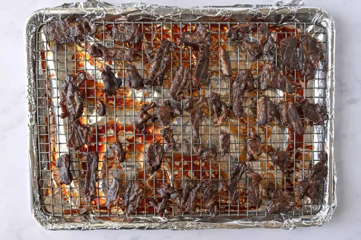 Cooked beef jerky on a baking sheet.