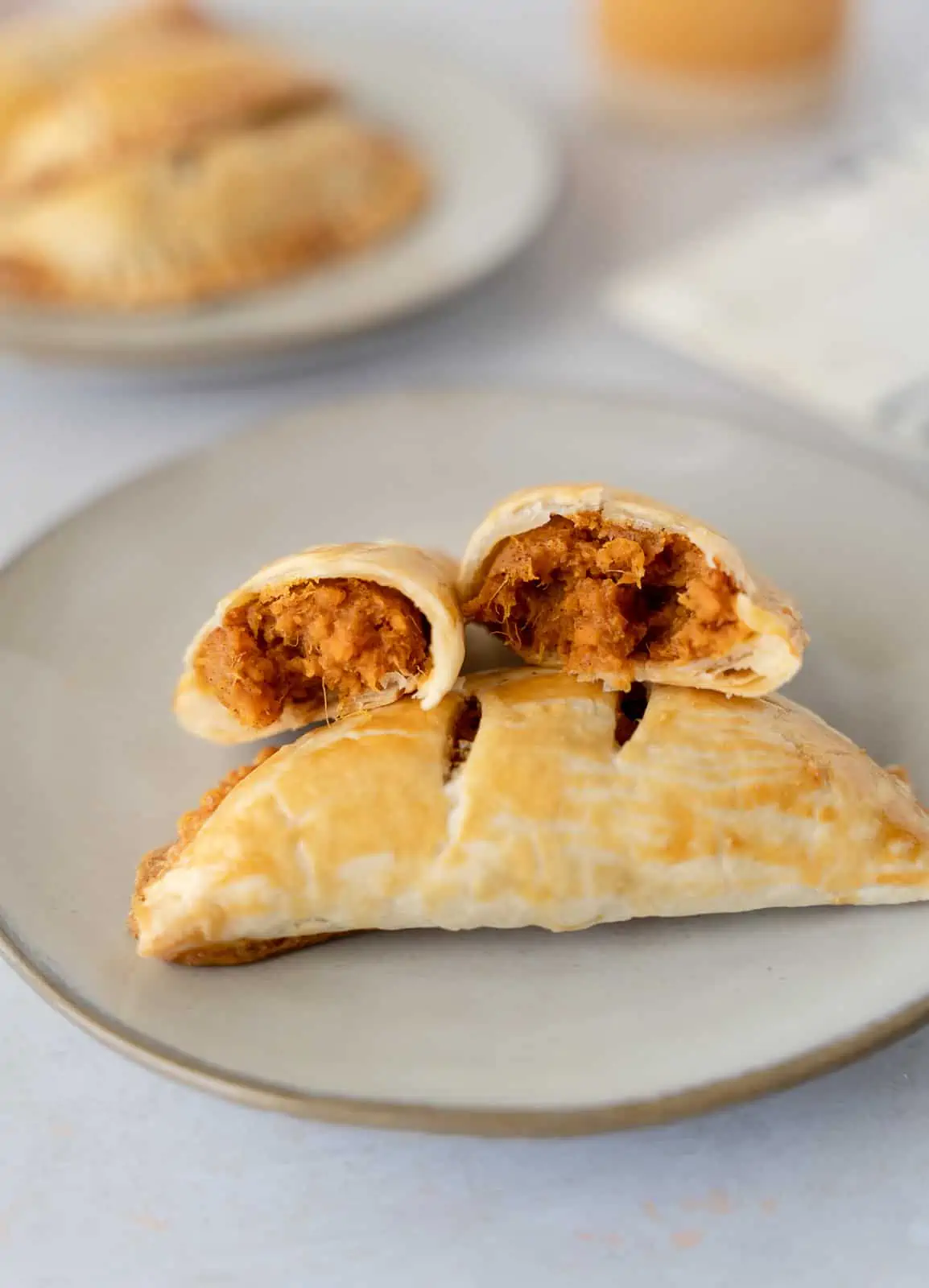 Empanadas on a plate with one broken in half to show sweet potato filling.
