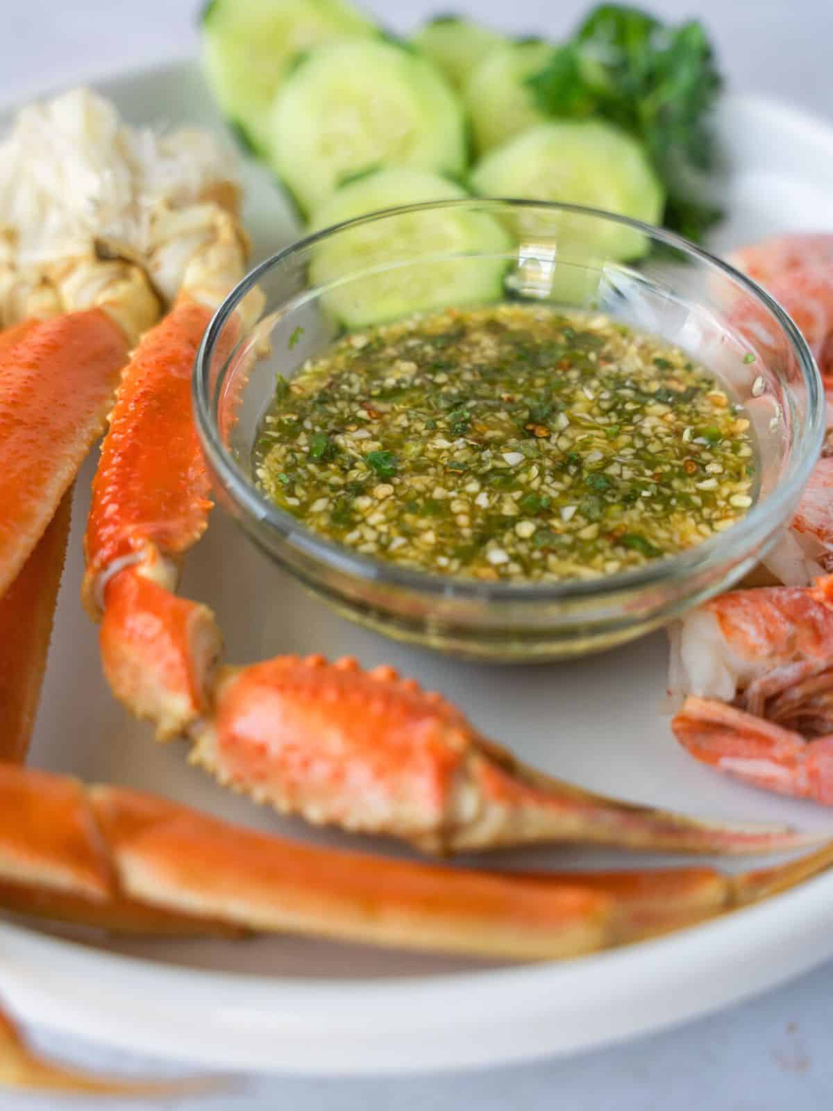 Up close view of seafood dipping sauce in a glass bowl with crab on the side.