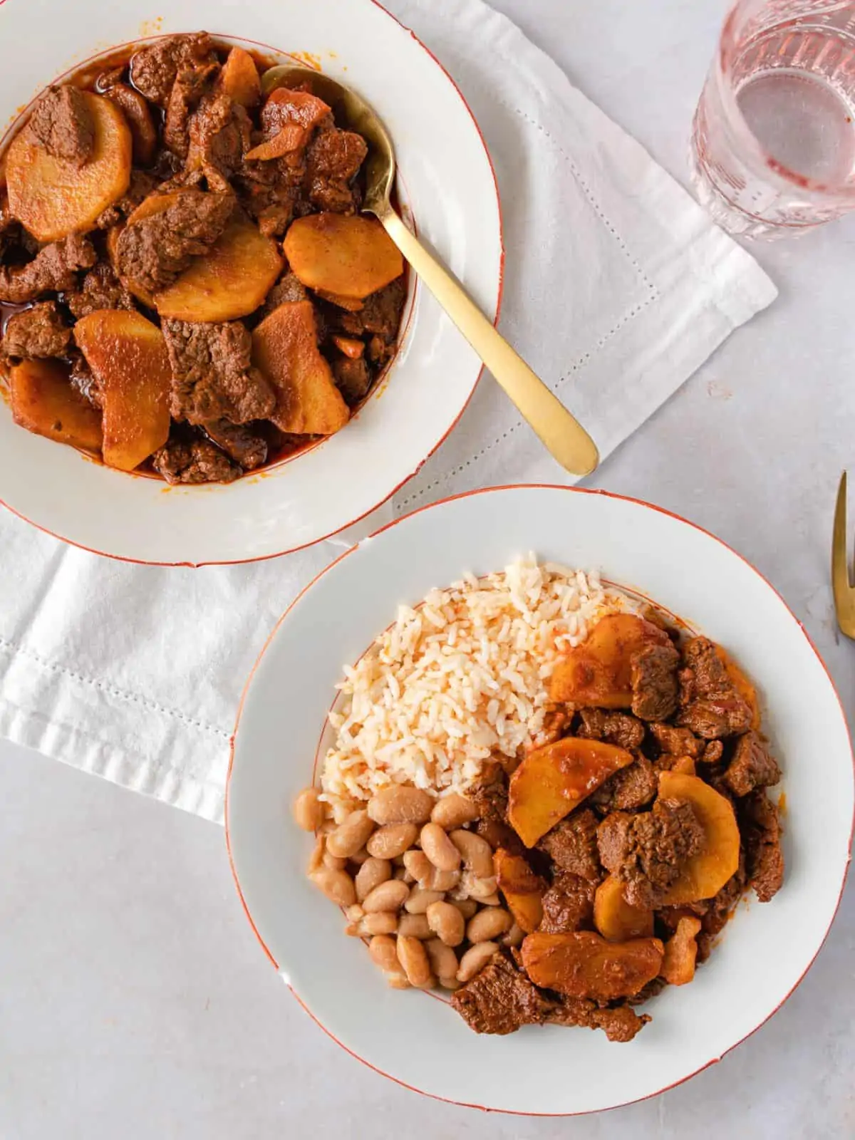 Two plate of carne con papas and one with rice and beans.
