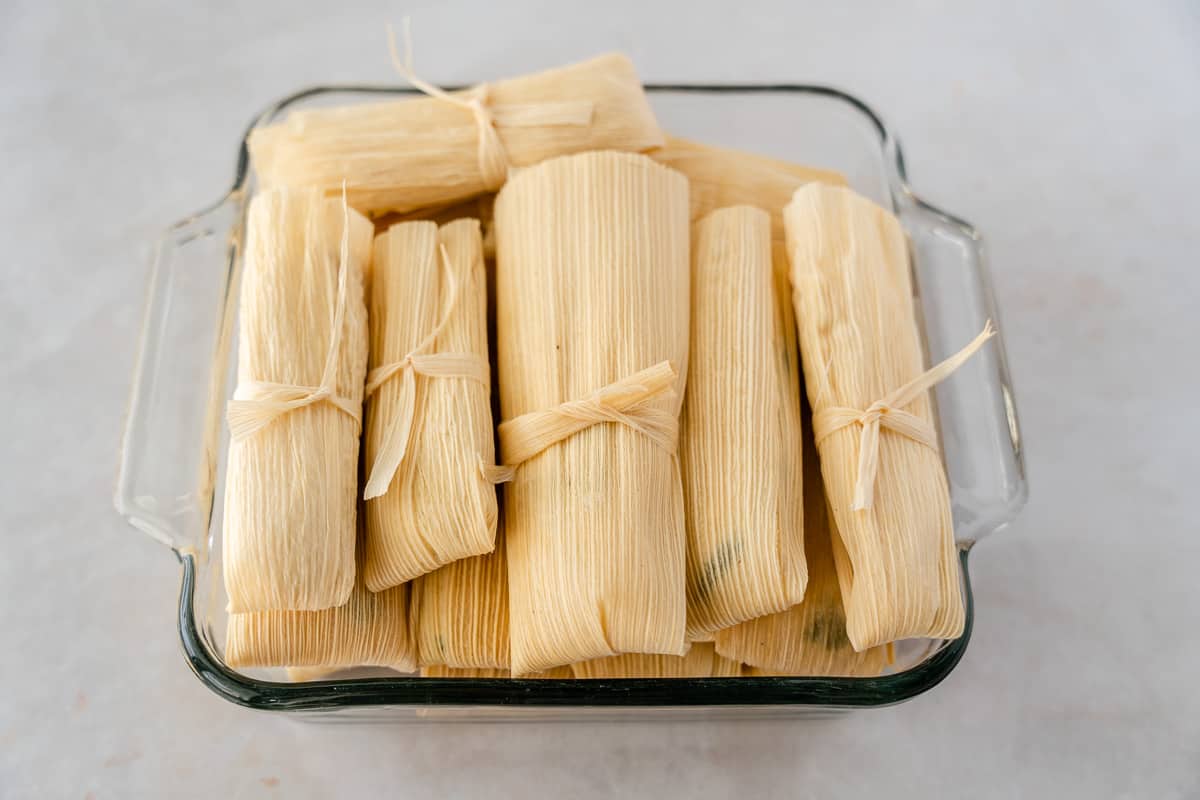 Wrapped tamales in a glass container.