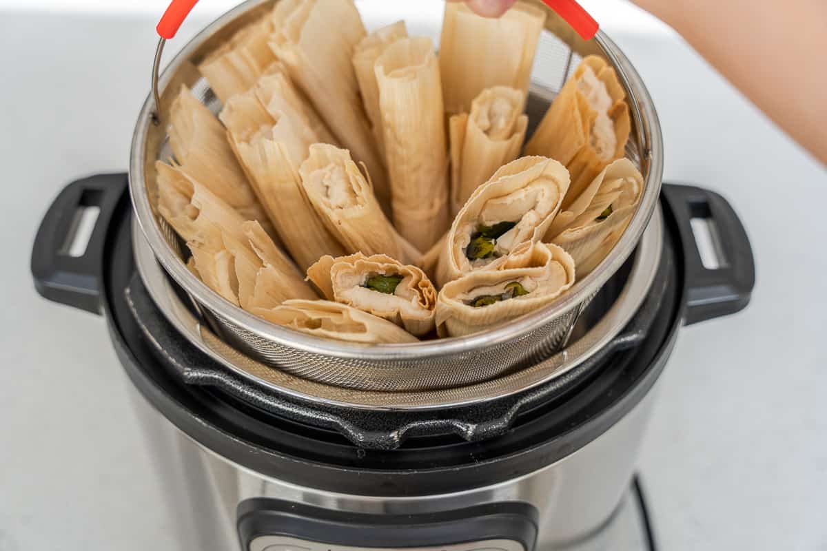 Tamales layered in a steamer basket in an instant pot.
