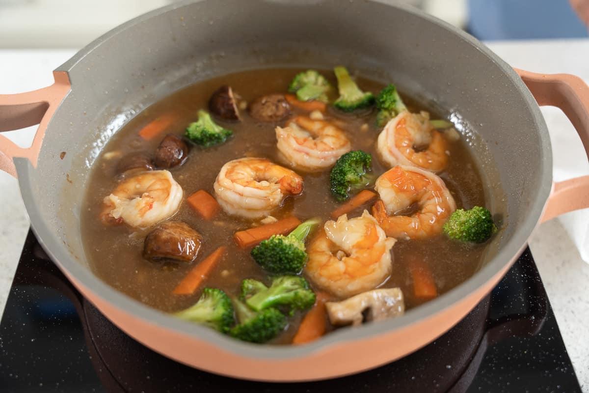 Gravy with vegetables and shrimp in a skillet.