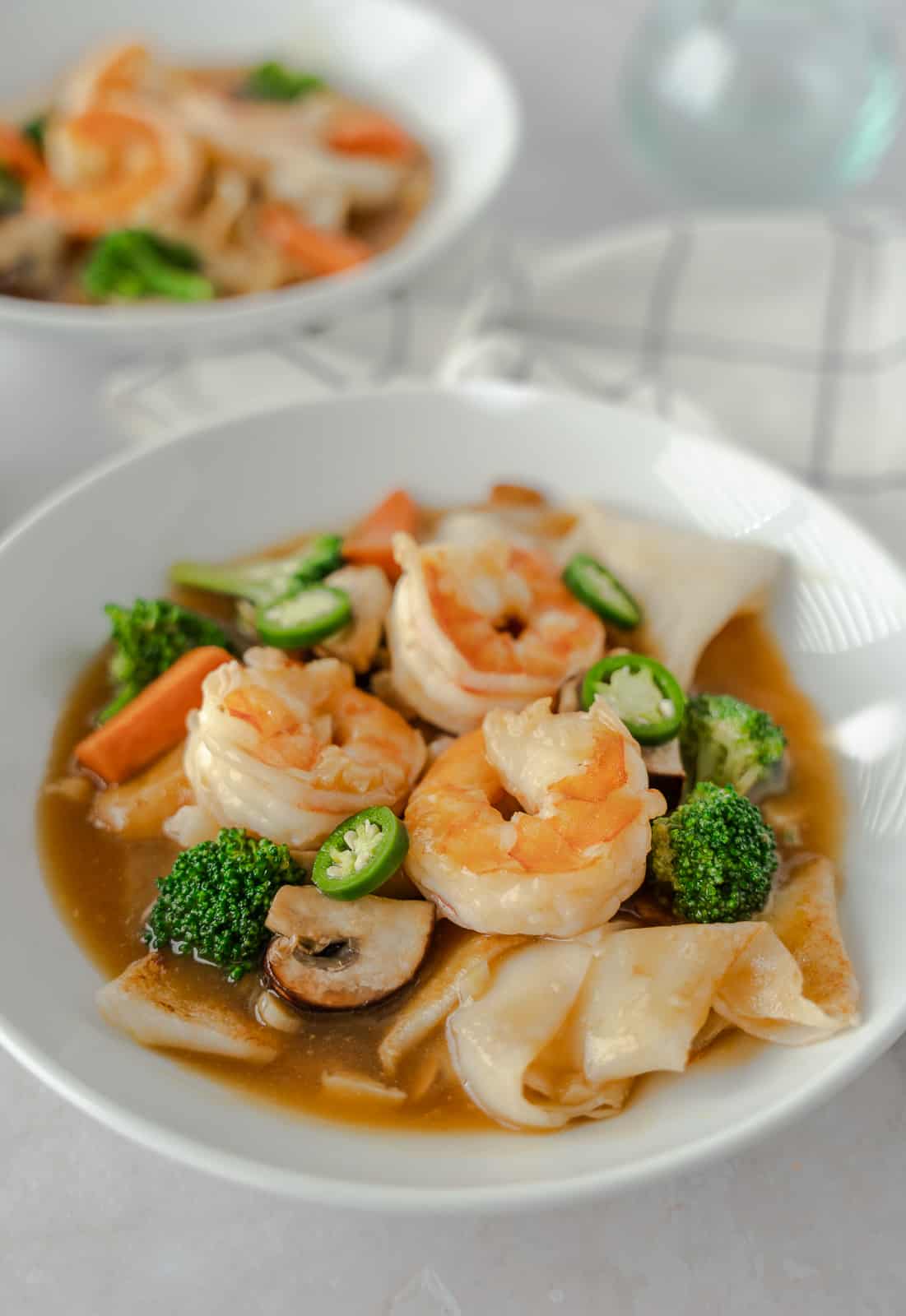 Up close view of noodle dish in a bowl with shrimp on top.