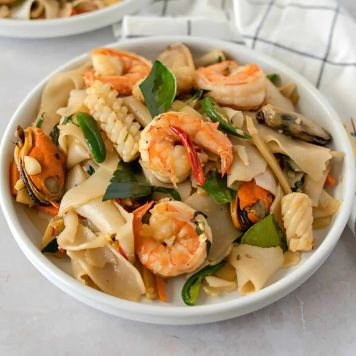 Feature image of pad kee mao with seafood on a plate.
