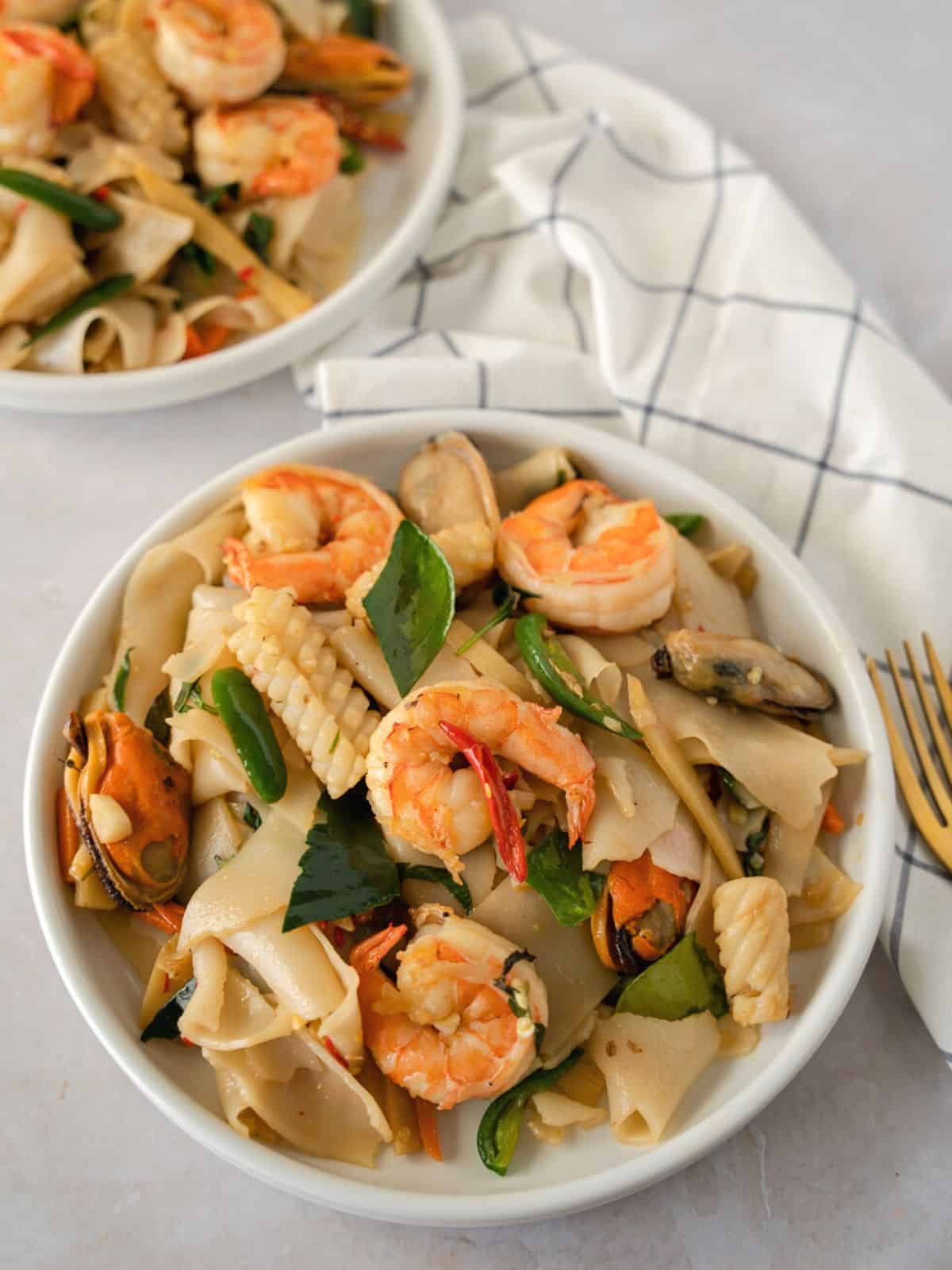 Thai drunken noodles with seafood on a 2 plates.