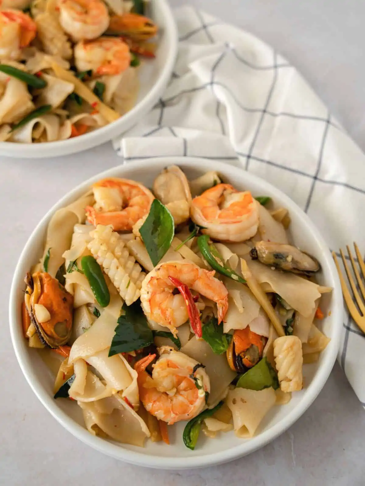 Thai drunken noodles with seafood on a 2 plates.