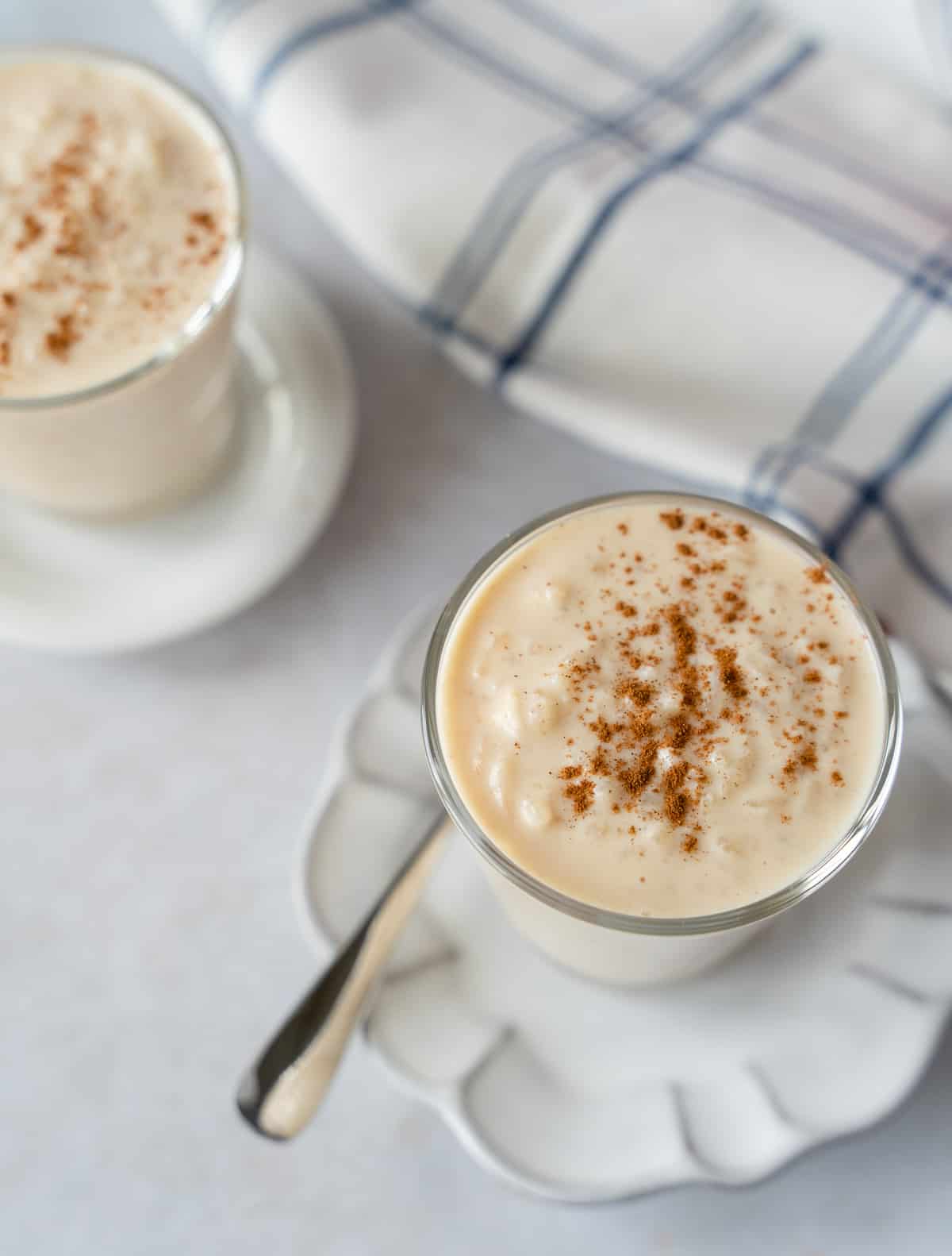 Overhead view of 2 cups of rice pudding topped with ground cinnamon.