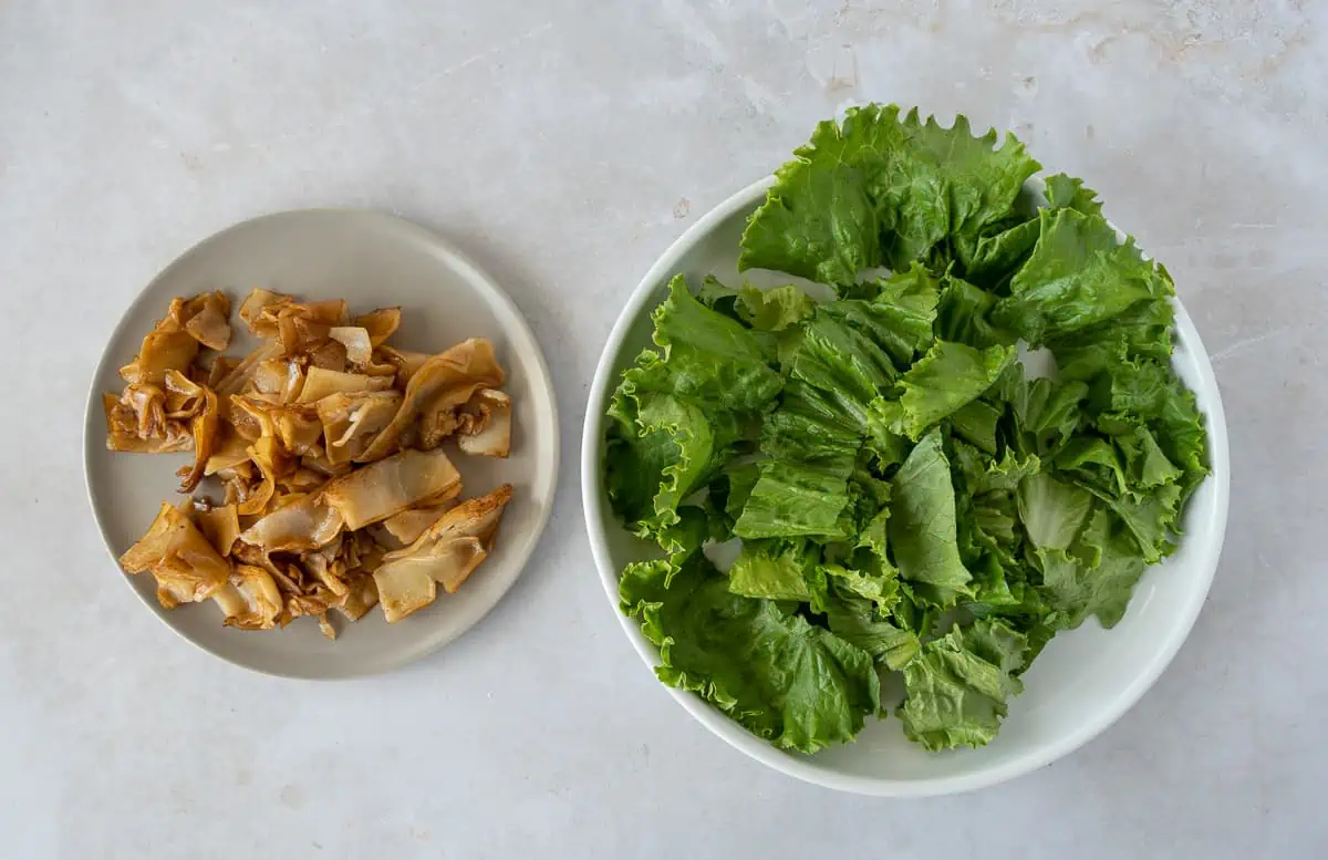 Noodles on one plate and lettuce on another plate.