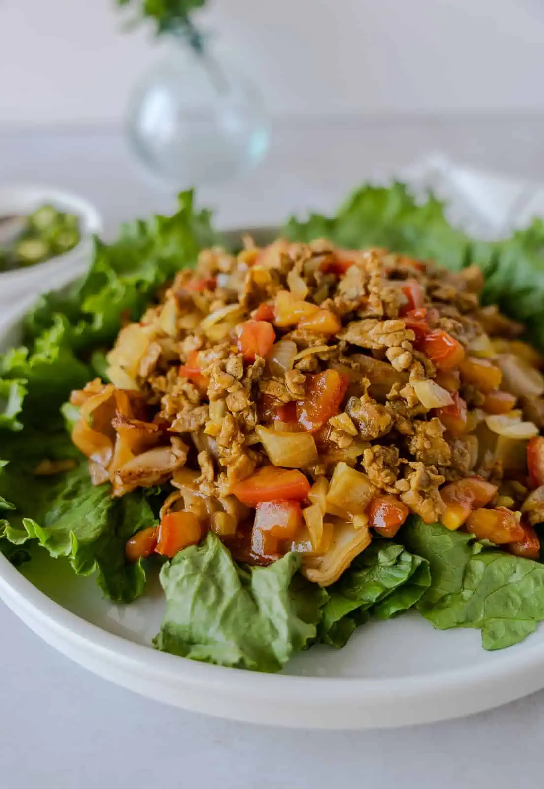 Finished plate of rice noodles with curried meat sauce on a bed of lettuce.