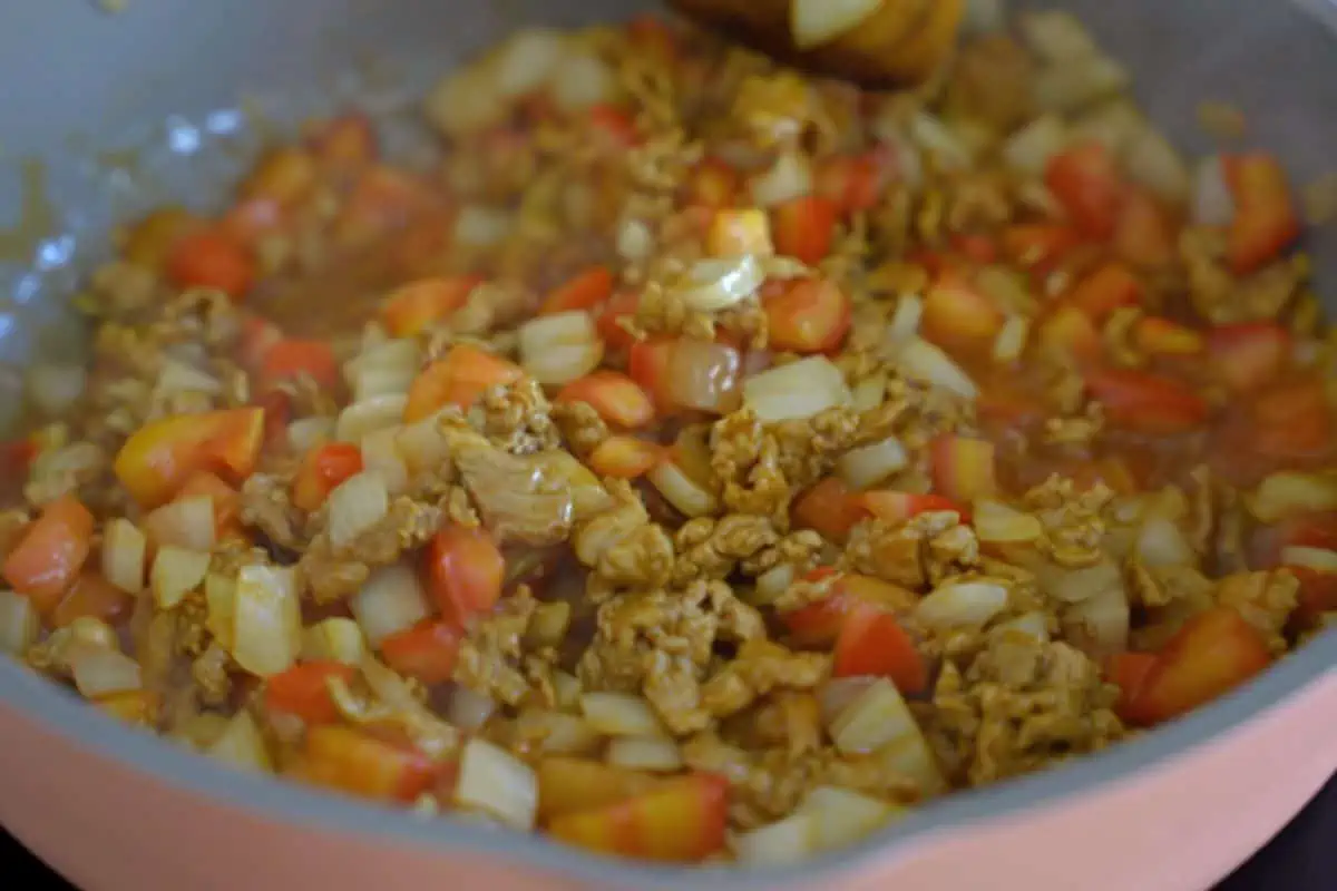 Meat sauce with onions and tomatoes in a skillet.