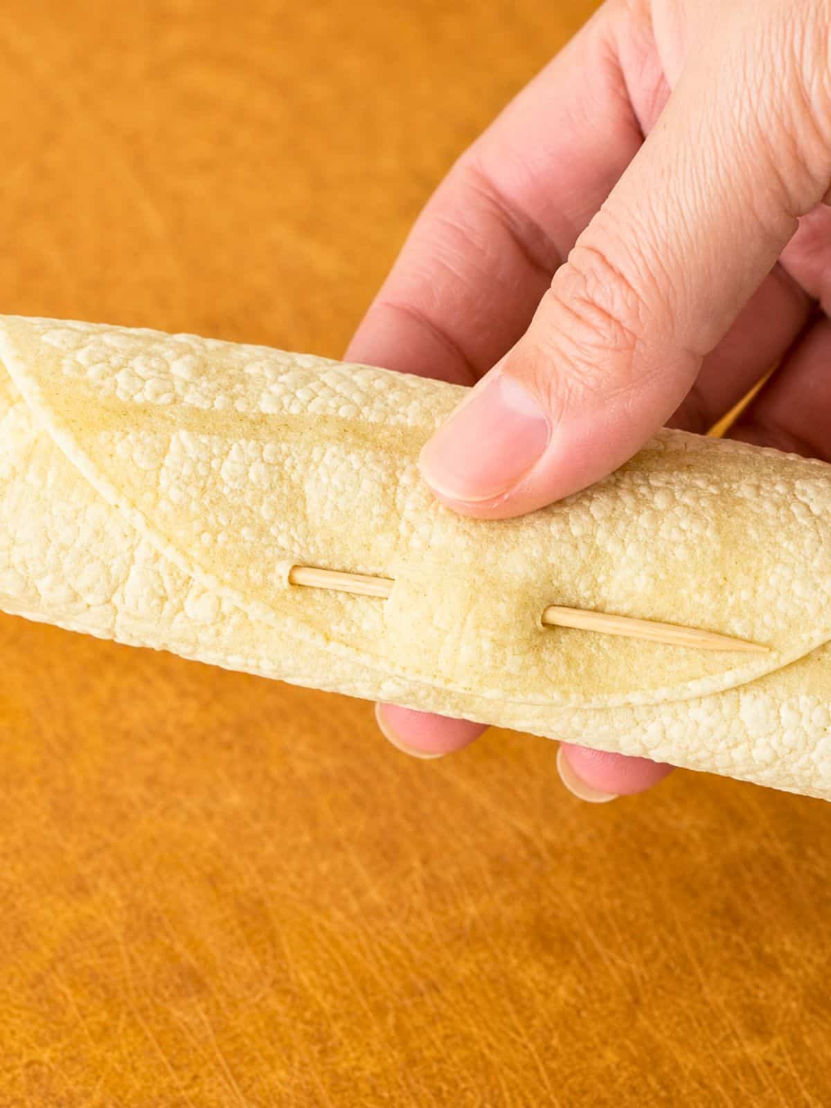 Rolled corn tortilla secured with a toothpick for Ground Beef Taquitos.