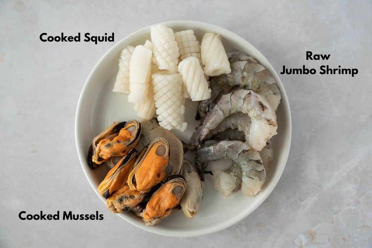 Squid, shrimp, and mussels on a white plate.