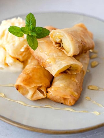 Feature image of fried banana spring rolls on a plate with ice cream.