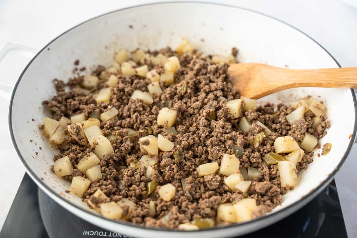 Cooked picadillo filling in a white skillet.