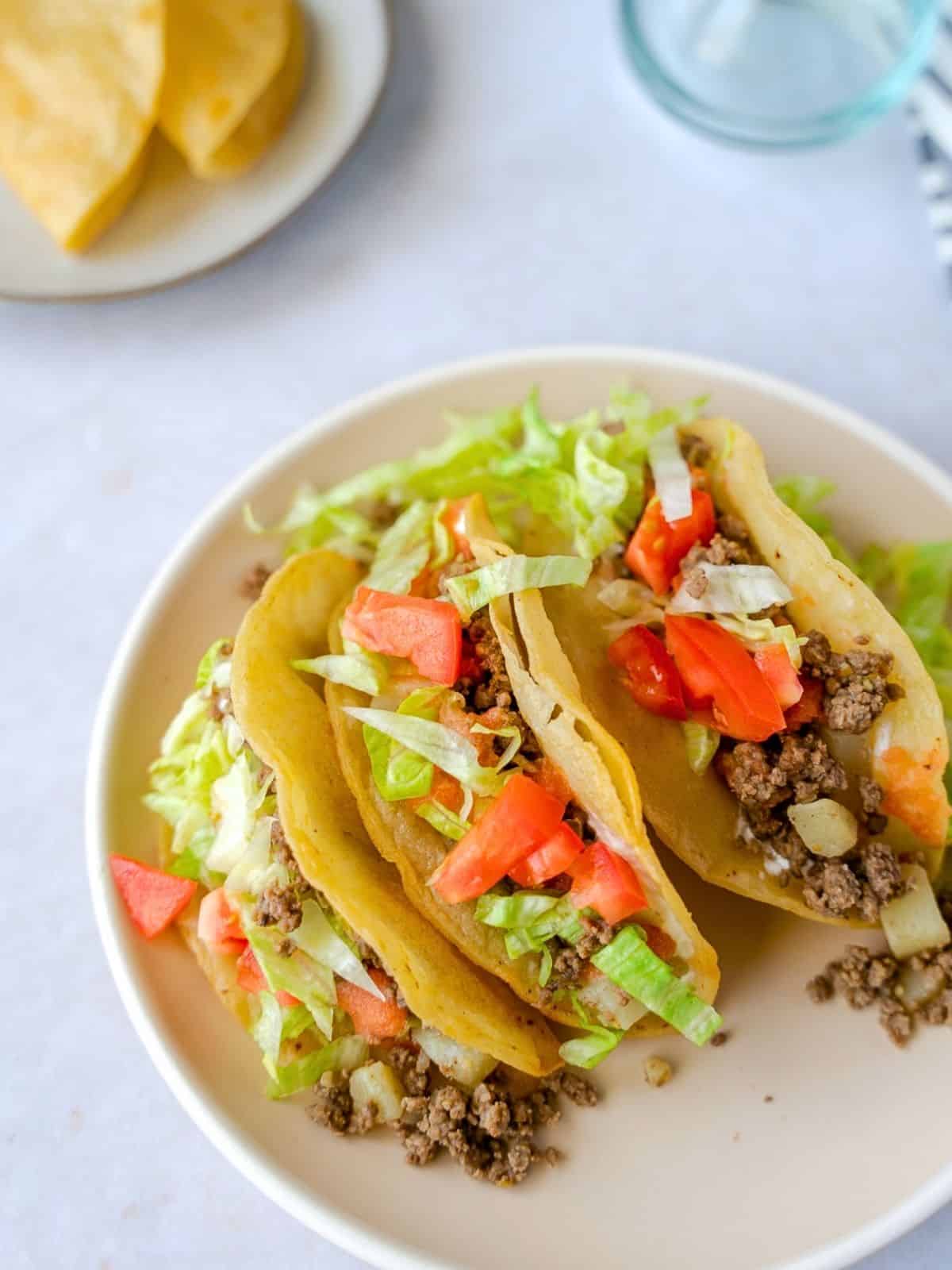 Three crispy Mexican picadillo tacos on a plate.