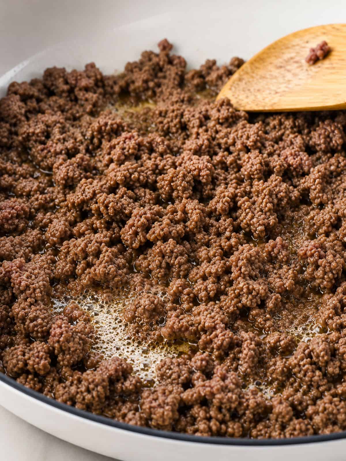 Ground beef browning in a skillet for Mexican picadillo.